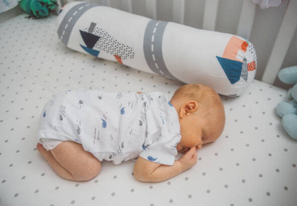 Baby sleeping on his stomach at crib